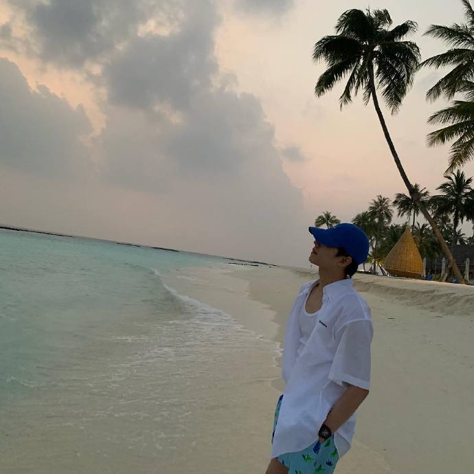 杨洋ins更新杨洋海边明信片身穿蓝色棒球帽白衬衫绿色短裤清新