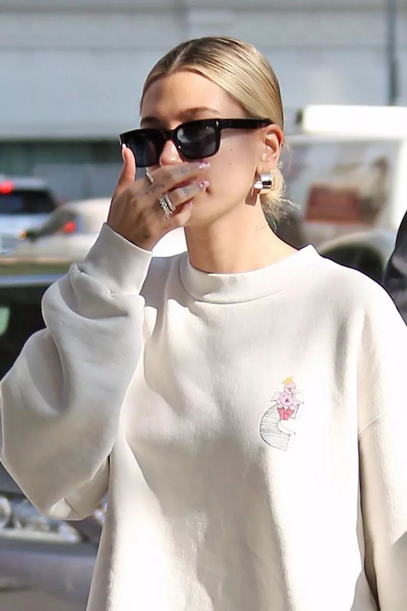 海莉白色卫衣套骑行裤,脚蹬帆布鞋好舒适,手捧鲜花心情不错