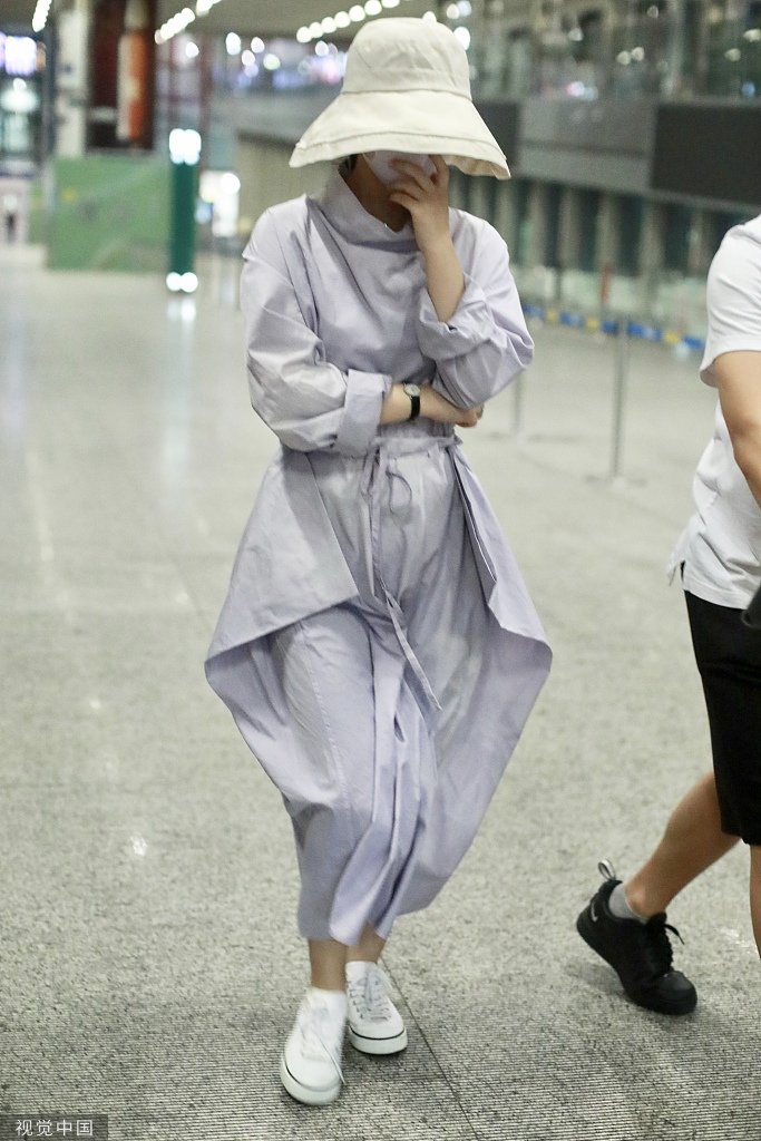 赵丽颖身穿蓝紫色长裙和白色帆布鞋现身机场,戴着帽子和口罩