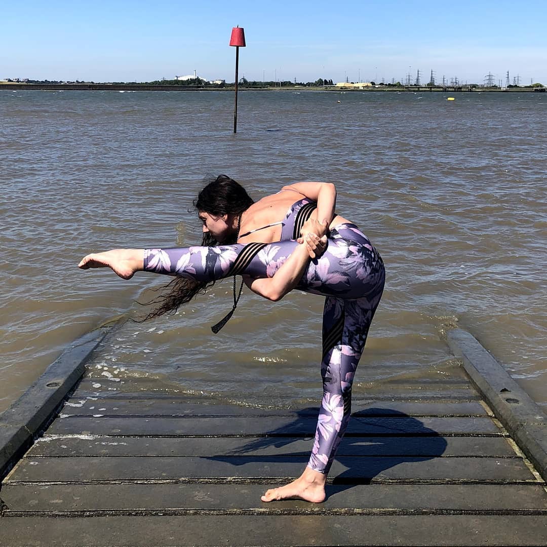 将左腿向前伸直抬起与地面保持水平,上半身前倾,双手去环绕住左腿大腿