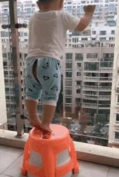 1岁宝宝踩凳子在8楼阳台玩,母亲不仅不阻止,还拿手机录视频