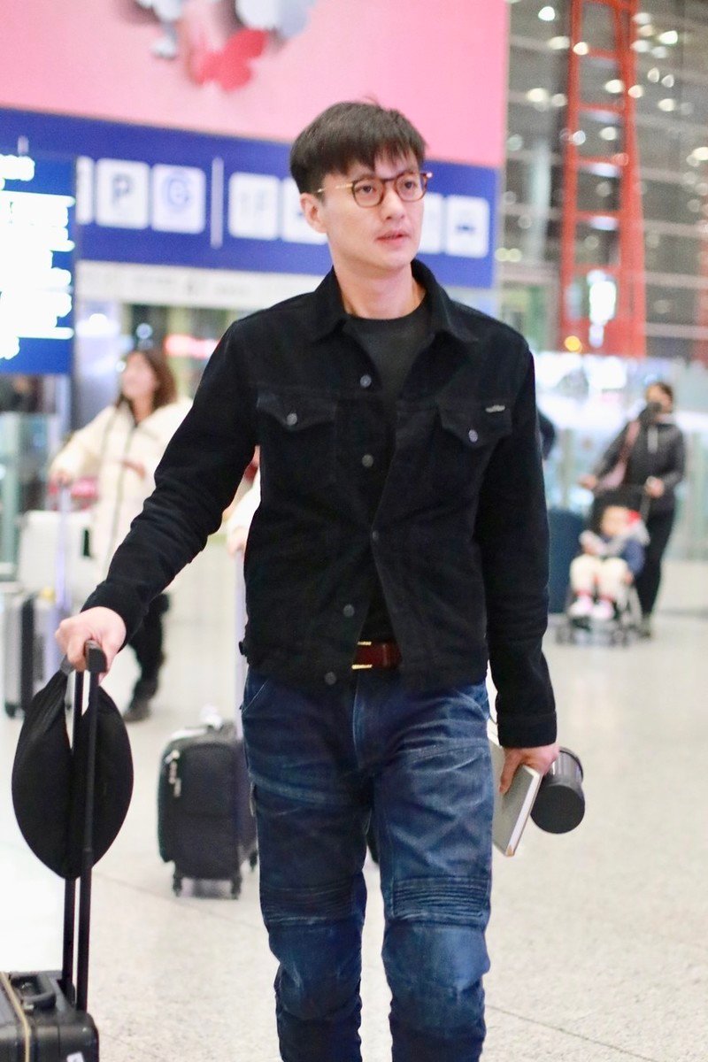 周一围手握保温杯走机场,戴镜框装"嫩",一低头暴露双下巴