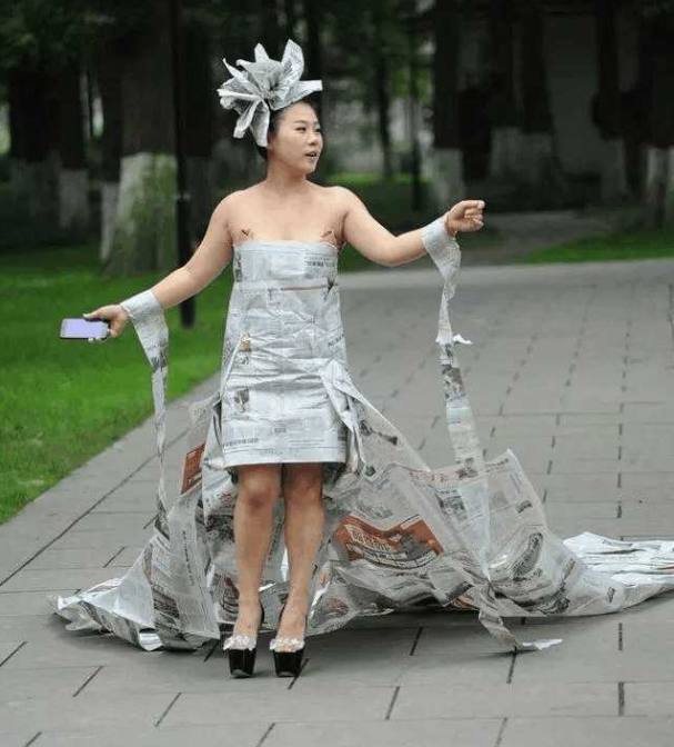 美女用报纸做成长裙穿在自己身上,引路人围观拍照