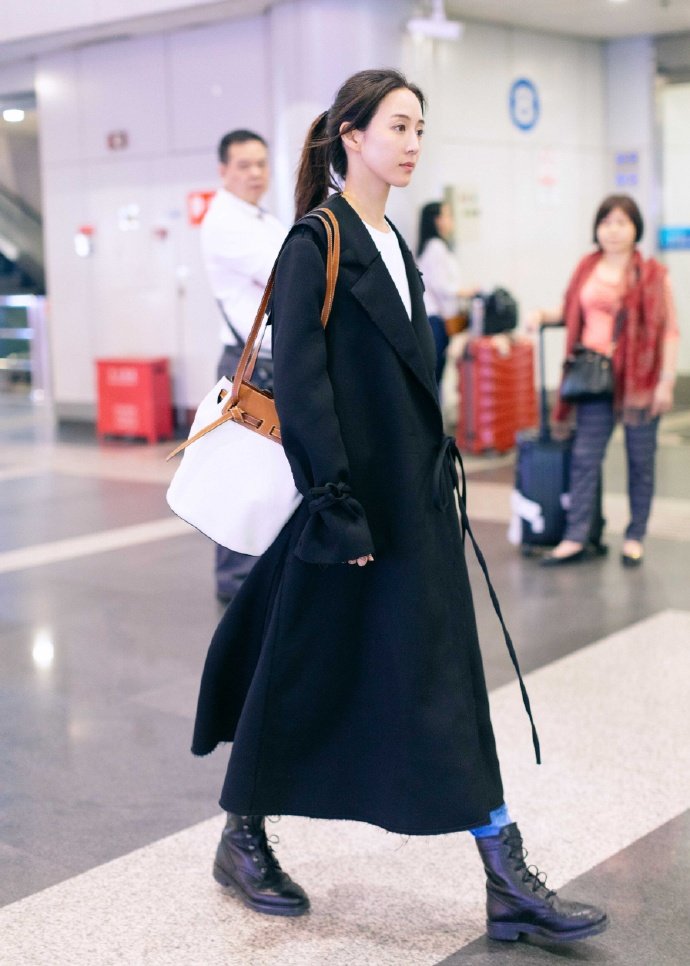 张钧甯身穿黑色抽绳长款大衣搭配拼色手提单肩包,加上黑色马丁靴|抽绳