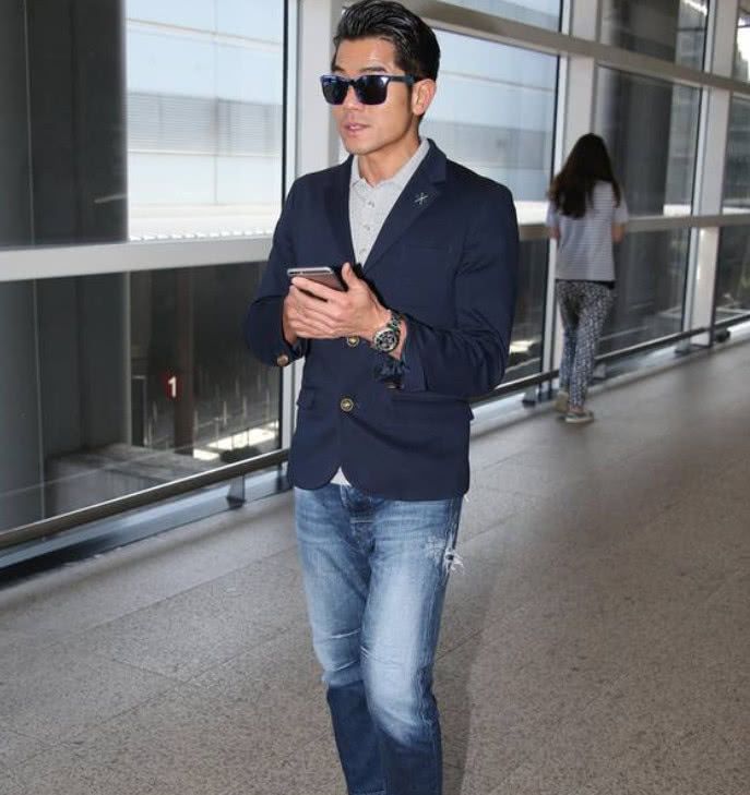 郭富城穿着一件深色的西装上衣配上一条深蓝色的牛仔裤,内搭着一件