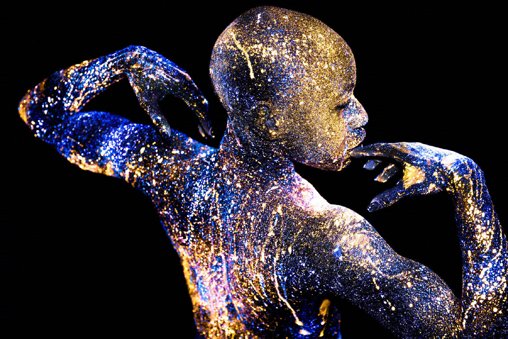 由荧光颜料彩绘的人体模特完全融入纯黑的背景