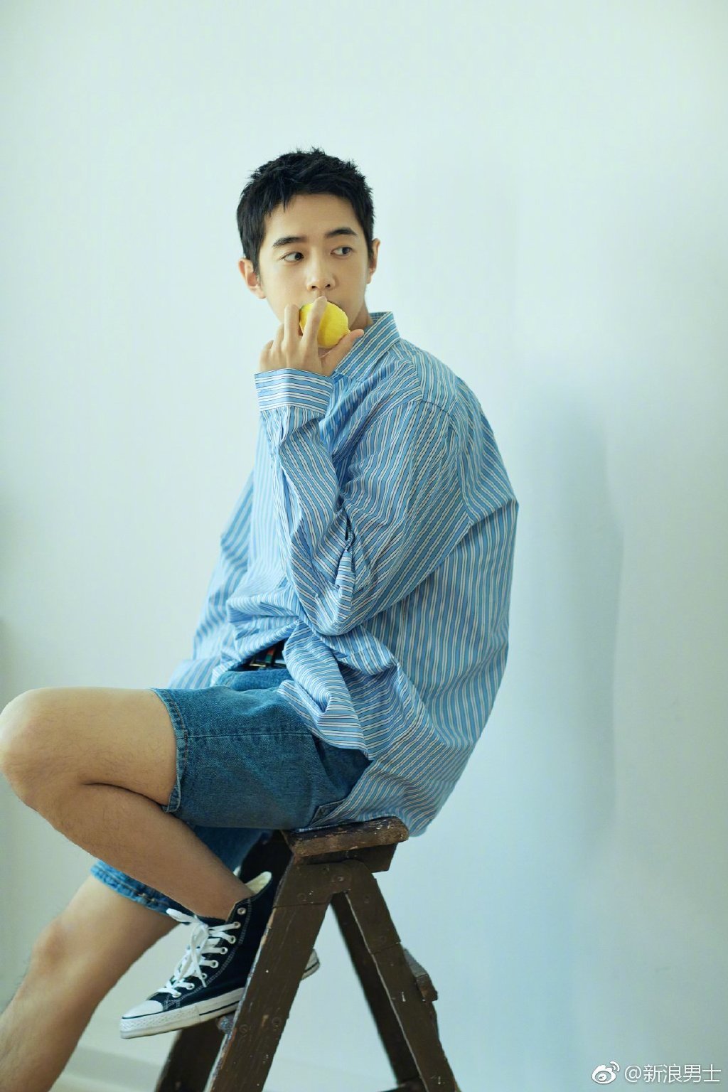 梁靖康身着蓝色条纹衬衫搭配牛仔短裤,清爽有型,随性自在