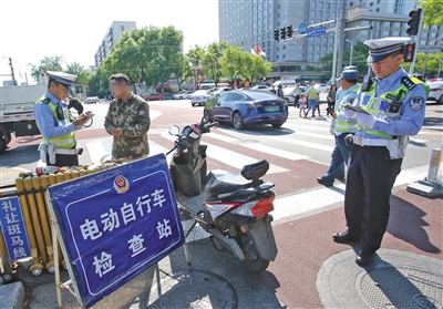 5月1日，宣武门路口，交警正在对一位有电动自行车临时标识但未悬挂的车主进行处罚。新京报记者 王贵彬 摄