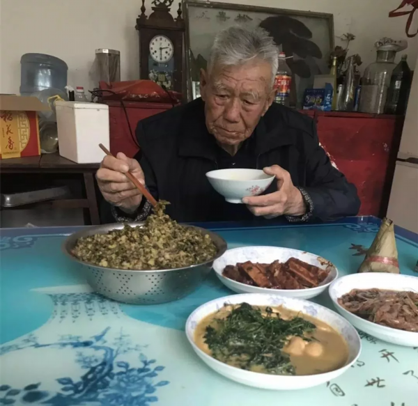 老人平时爱喝玉米糁粥,还喜欢看报纸,僮子戏