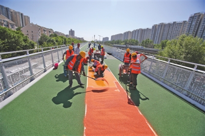5月23日,北京市政路桥养护集团施工人员铺装自行车专用路彩色面层。新京报记者 王贵彬 摄