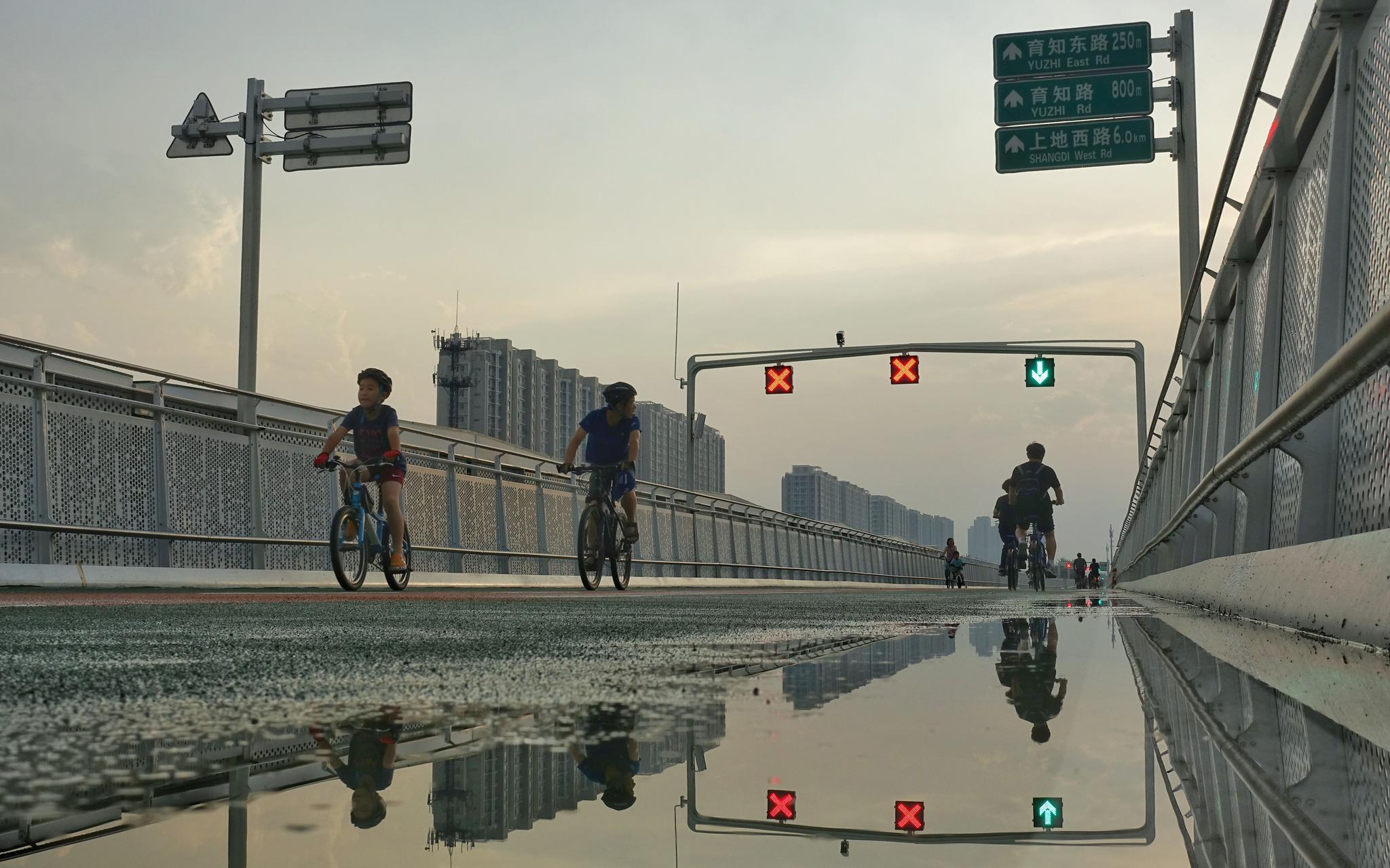 降雨过后，自行车专用路的路面出现了小范围的积水，市民骑行通过时，自觉放慢了车速。新京报记者 裴剑飞 摄
