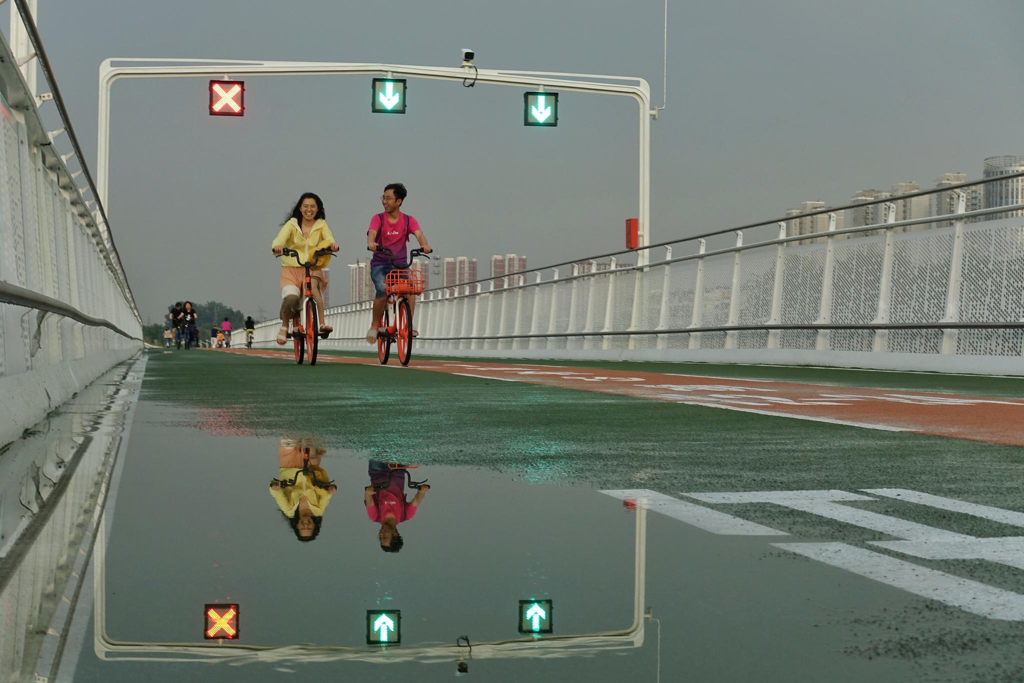 降雨过后，自行车专用路的路面出现了小范围积水，市民骑行通过时，自觉放慢了车速。新京报记者 裴剑飞 摄