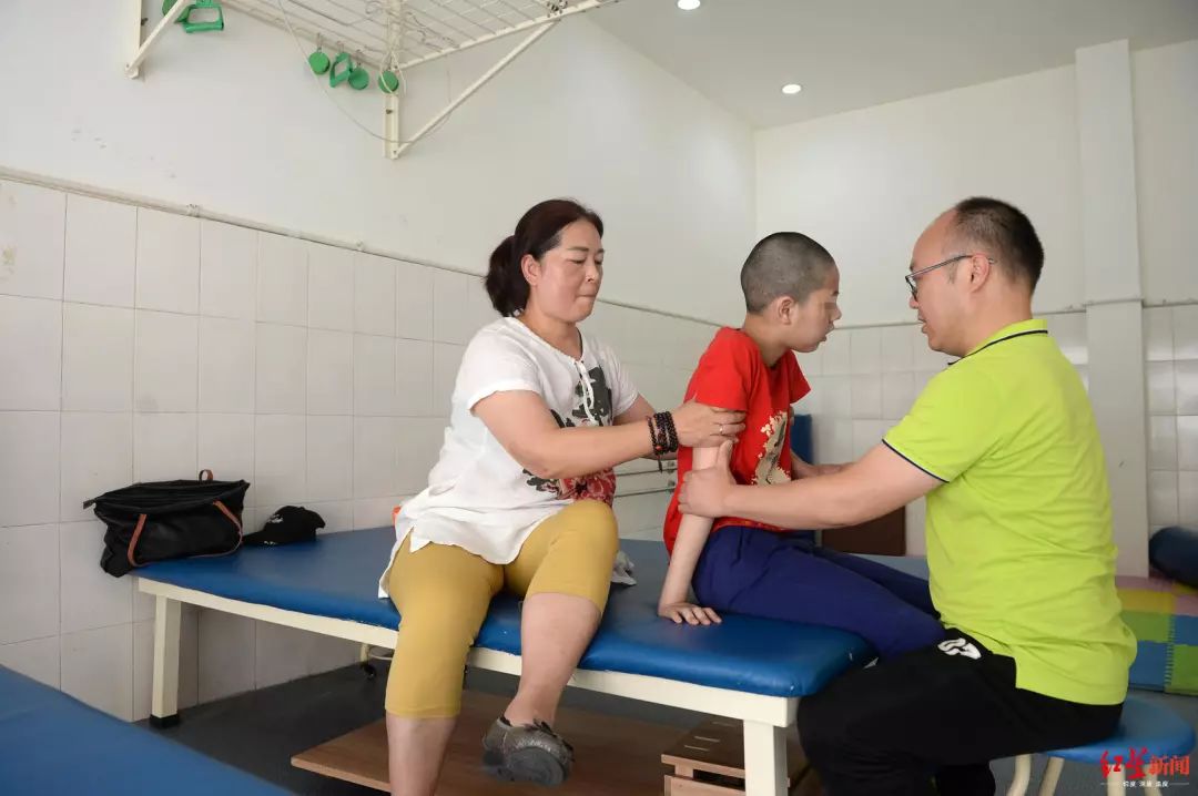 2019年6月4日成都，谢芳协助康复师帮孩子完成康复动作。（王效 摄）