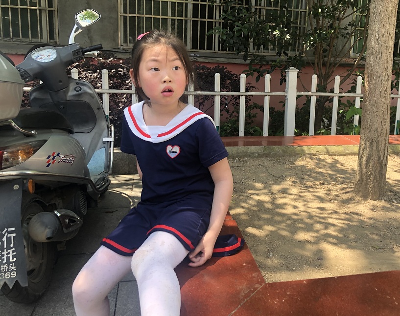  在学校操场上坐着的小女孩。新京报记者 田杰雄 摄