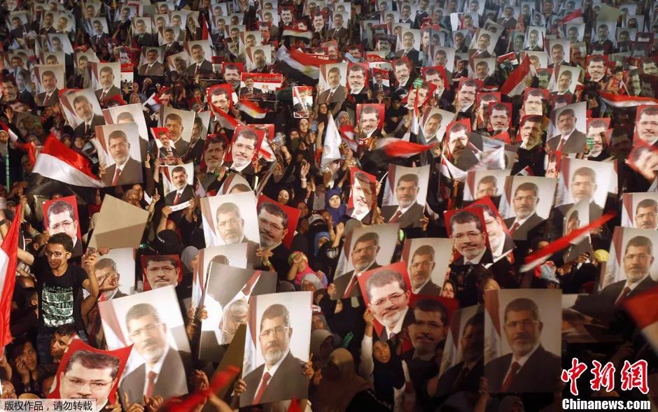 资料图：2013年7月，埃及开罗，穆尔西支持者在一处清真寺广场高举穆尔西肖像以示抗议。