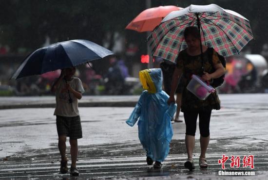 资料图：市民冒着大雨出行。 张斌 摄