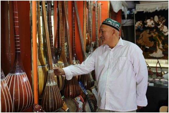 吐尔孙尼亚孜正在寺旁的乐器店认真挑选"都塔尔"(一种维吾尔乐器)