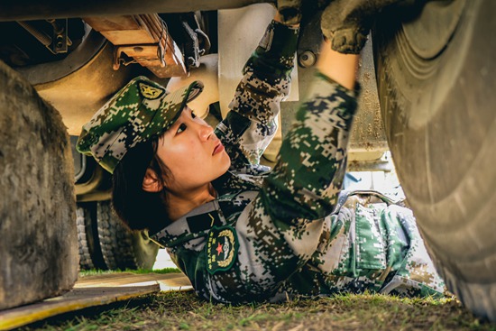 运输分队一名女兵正在对运输车的制动系统进行检查.