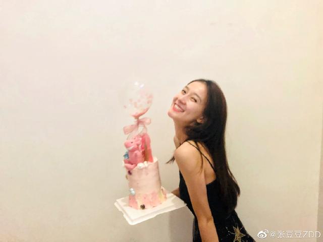 长发披肩笑容甜美的张豆豆,手里捧着一个造型告别的生日蛋糕,女神范