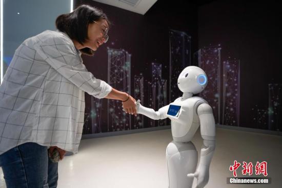  资料图：一名参观者与5G+智能机器人“小5”握手。中新社记者 贺俊怡 摄