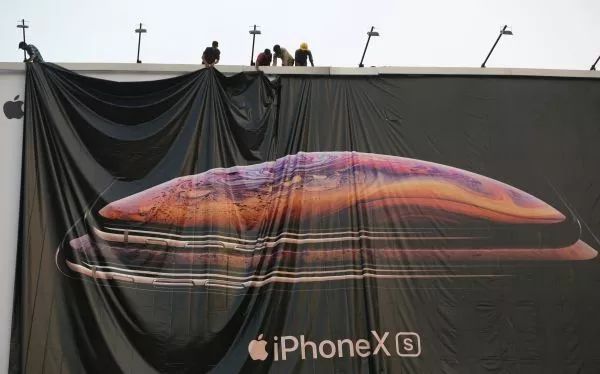 ▲资料图片：印度艾哈迈达巴德，工人正在调整苹果iPhone X的宣传海报。（路透社）
