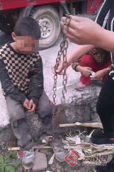 　小男孩脚被铁链锁住的视频截图。  本文图片均来自云南网