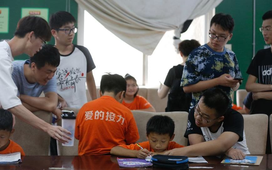 7月26日下午，志愿者在帮孩子们辅导功课。新京报记者 侯少卿 摄