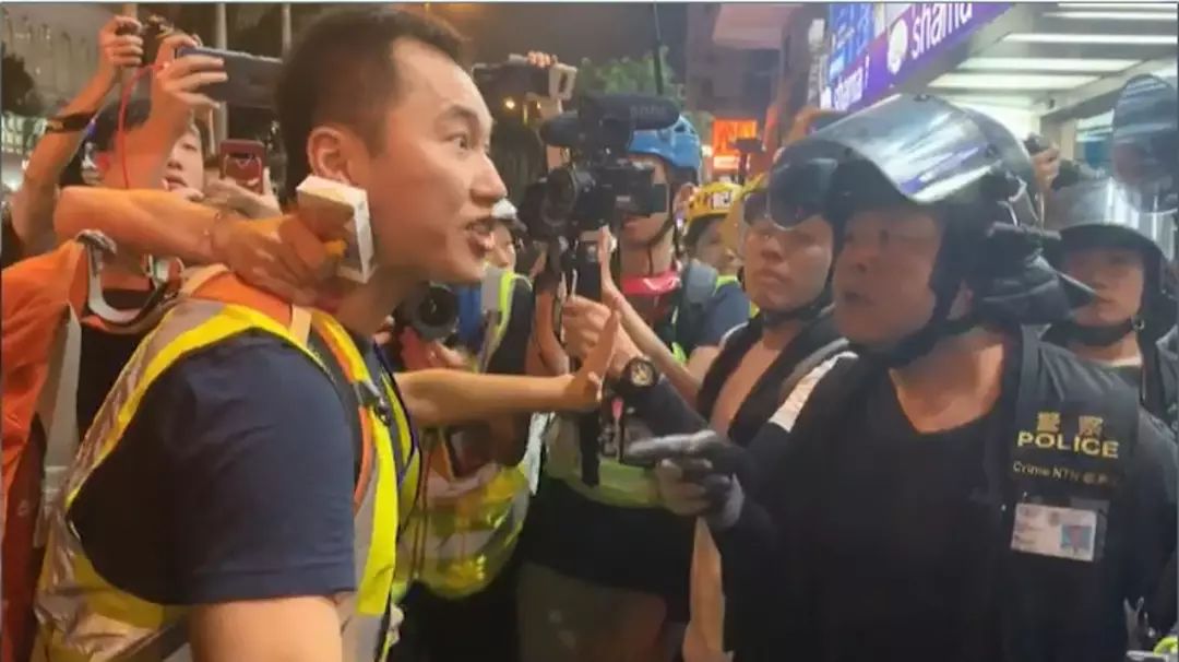 8月11日尖沙咀冲突中，许锐宇（左）身着“记者黄背心”，与在场警员对骂（来源：港媒）