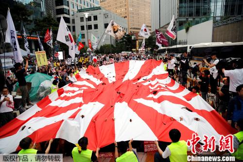 　资料图：韩国民众撕扯着旭日旗，在日本驻韩使馆前抗议。