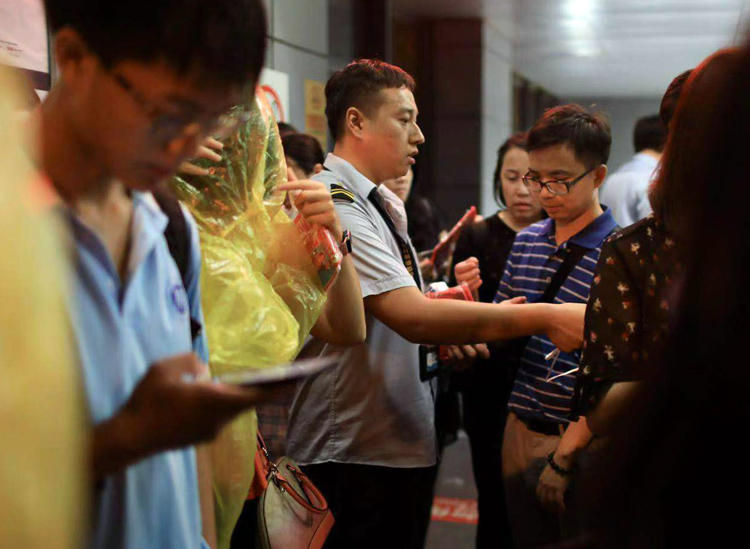 北京暴雨 地铁 地铁10号线莲花桥站,工作人员为市民免费提供一次性雨衣。