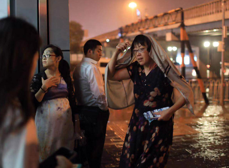 北京暴雨 地铁 市民在地铁站出口处等雨停。