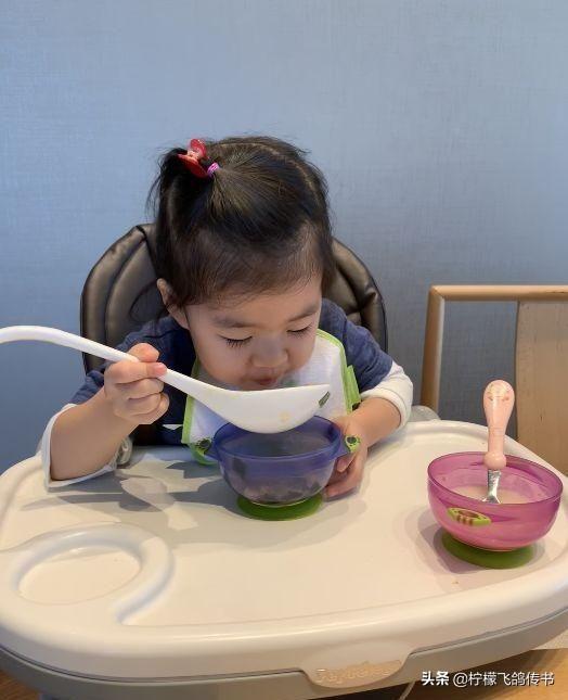 醒宝坐在婴儿桌里非常认真的吃饭,桌子上保持得非常的干将,那个碗的