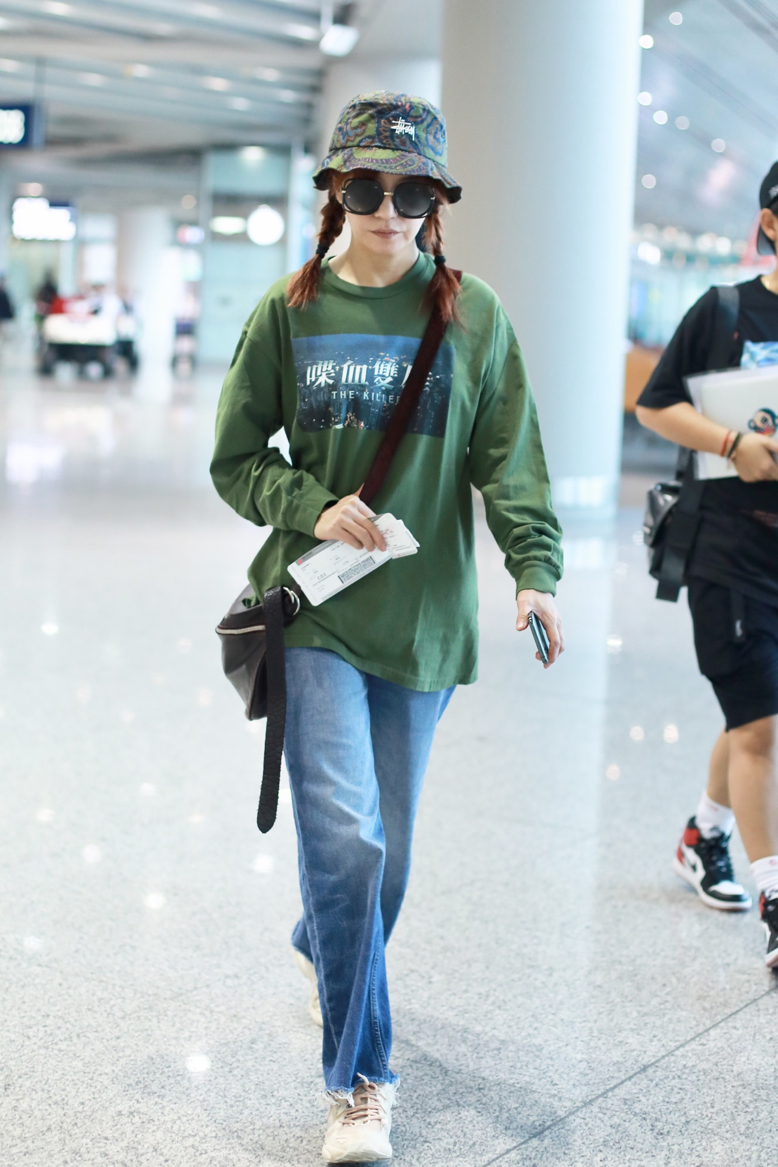 近日赵薇现身机场,她头戴绿色渔夫帽,扎着两个麻花辫,造型青涩少女感