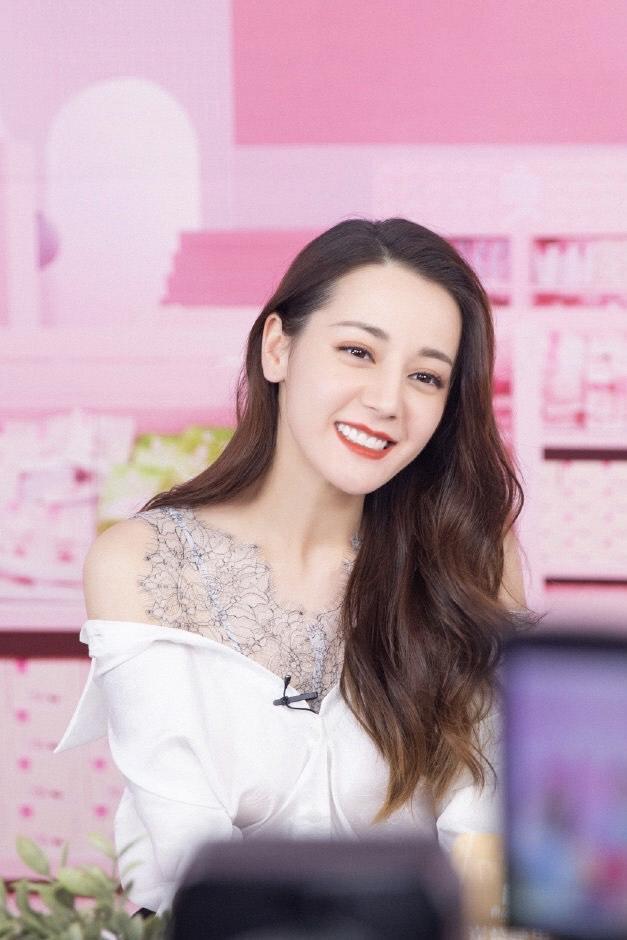 迪丽热巴留一款卷发造型优雅大气,身穿白上衣搭配黑色色裙