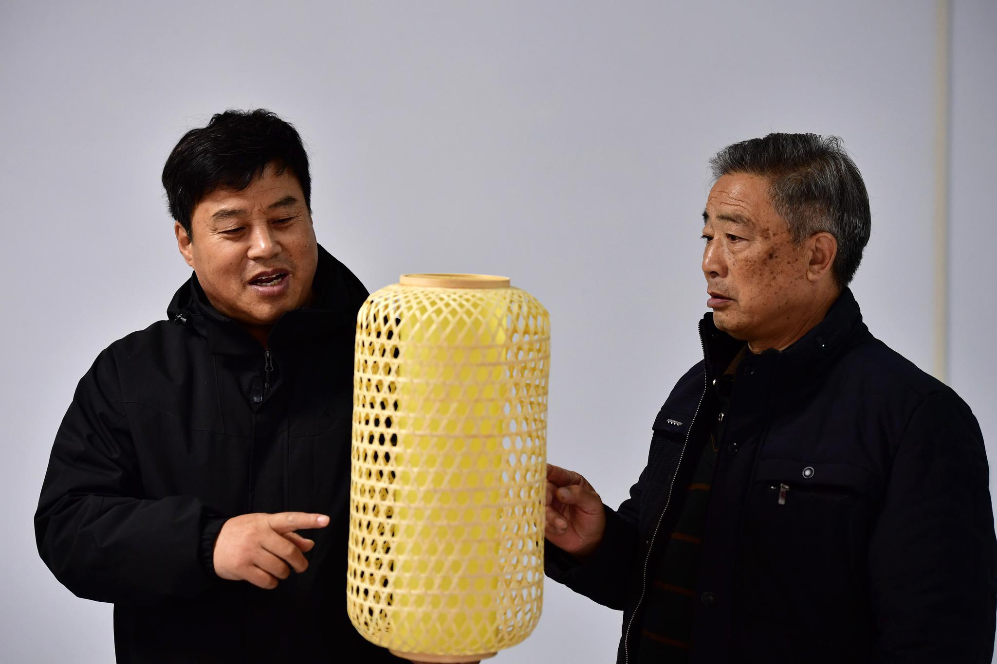 张永杰(右)向洛宁县文化馆馆长段慧博介绍宫灯状的竹编作品