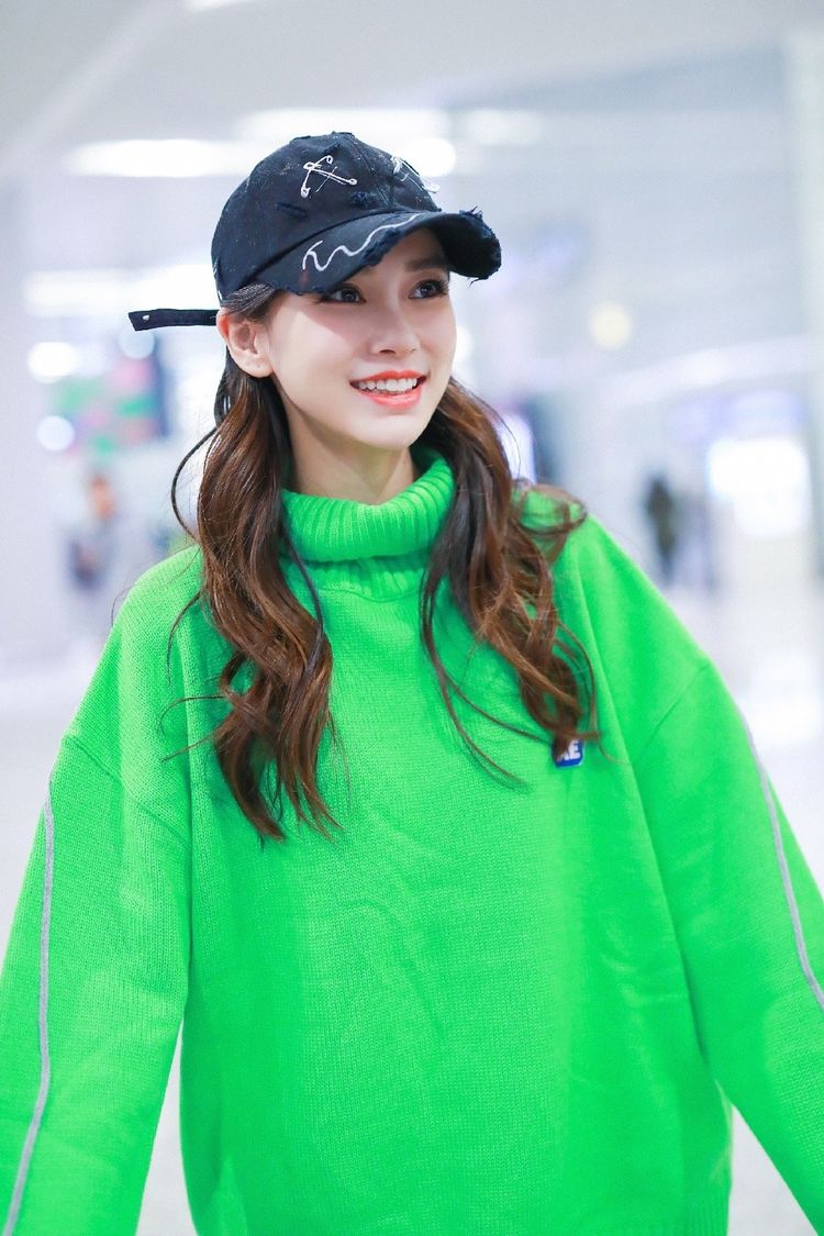 杨颖美成机场焦点穿绿色针织衫戴鸭舌帽笑容明媚少女感十足