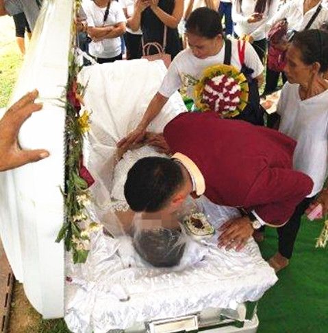 仪式上,杨柳安详地躺着,身穿漂亮的白色婚纱,身边被粉红色的鲜花包围