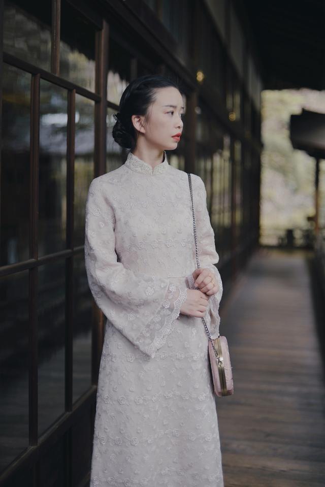 气韵盎然,旗袍裙线条柔婉曼妙,立领衔接着斜襟,绿色珠扣点缀,莹润透彻