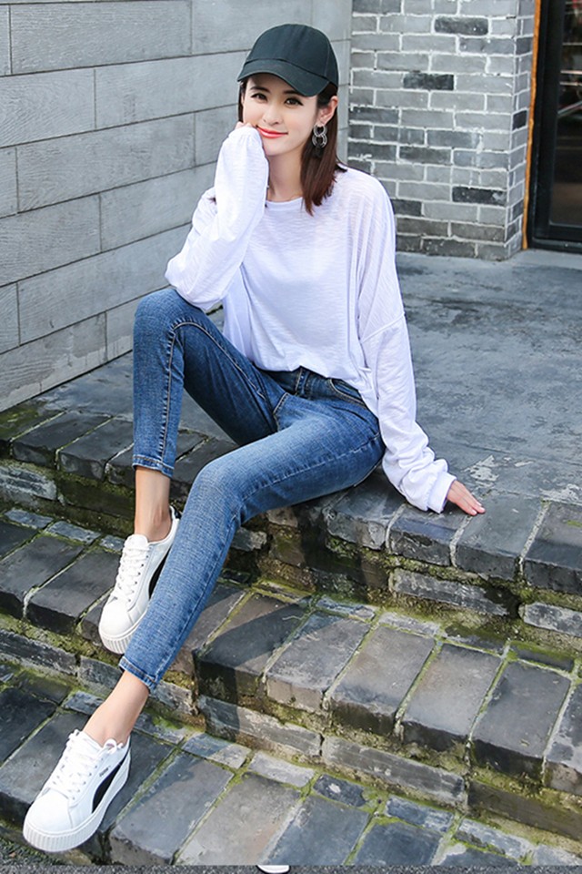 牛仔裤美女坐在梯子上戴着黑帽搭配小白鞋看起来真时尚