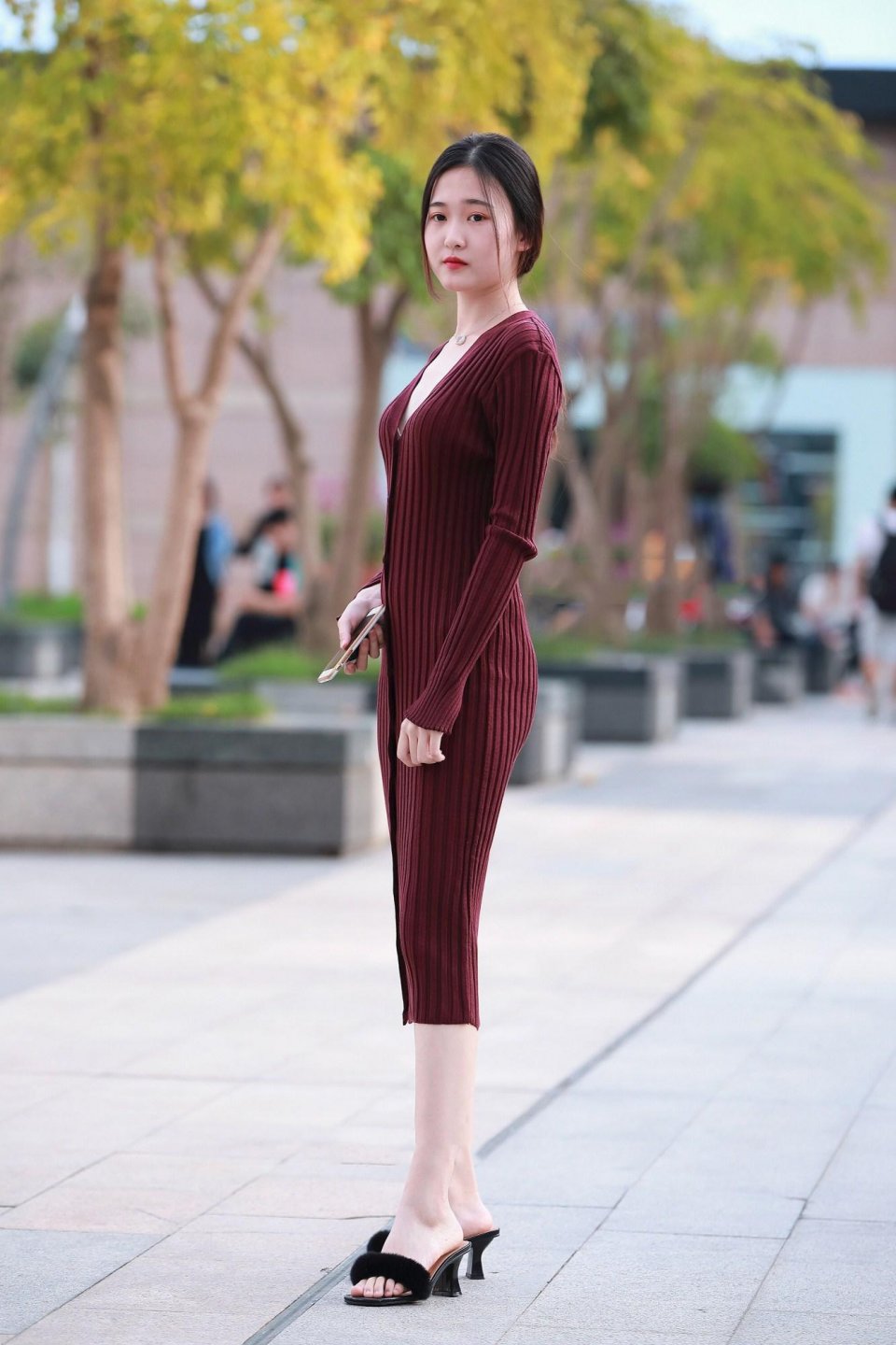 街拍身穿酒红色针织紧身长裙的苗条少女