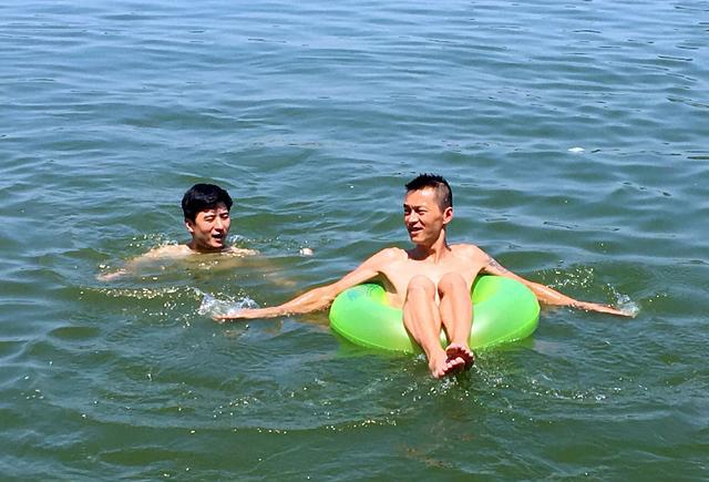 灞河成了民众避暑降温的天然泳池,市容管理人员在岸上喊不要下河游泳