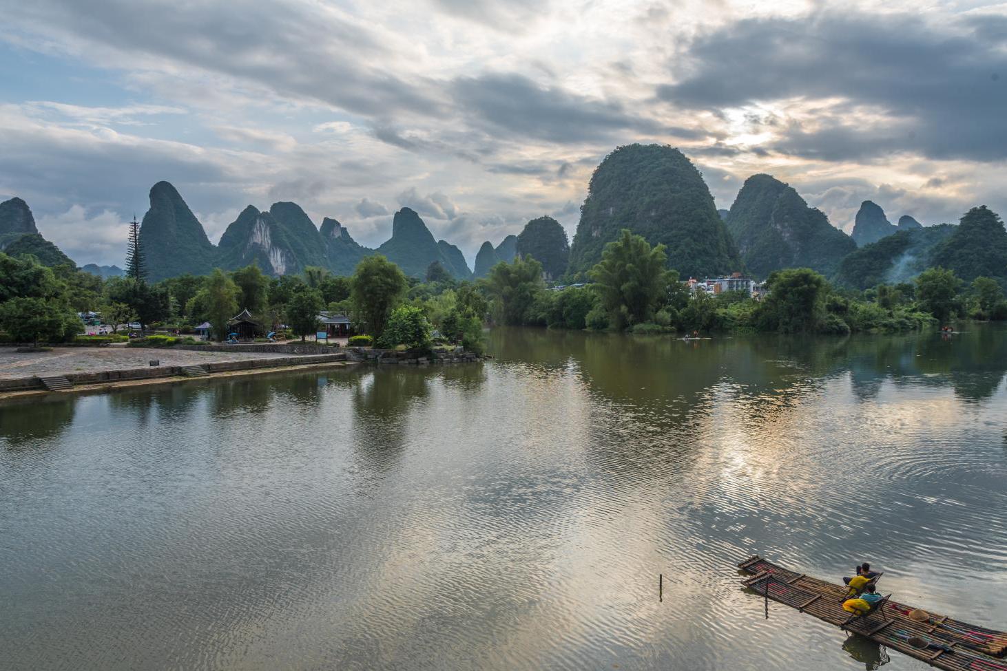 榕树,在一个桥上,很多人将车停在路边,站在桥上欣赏着美丽的漓江山水