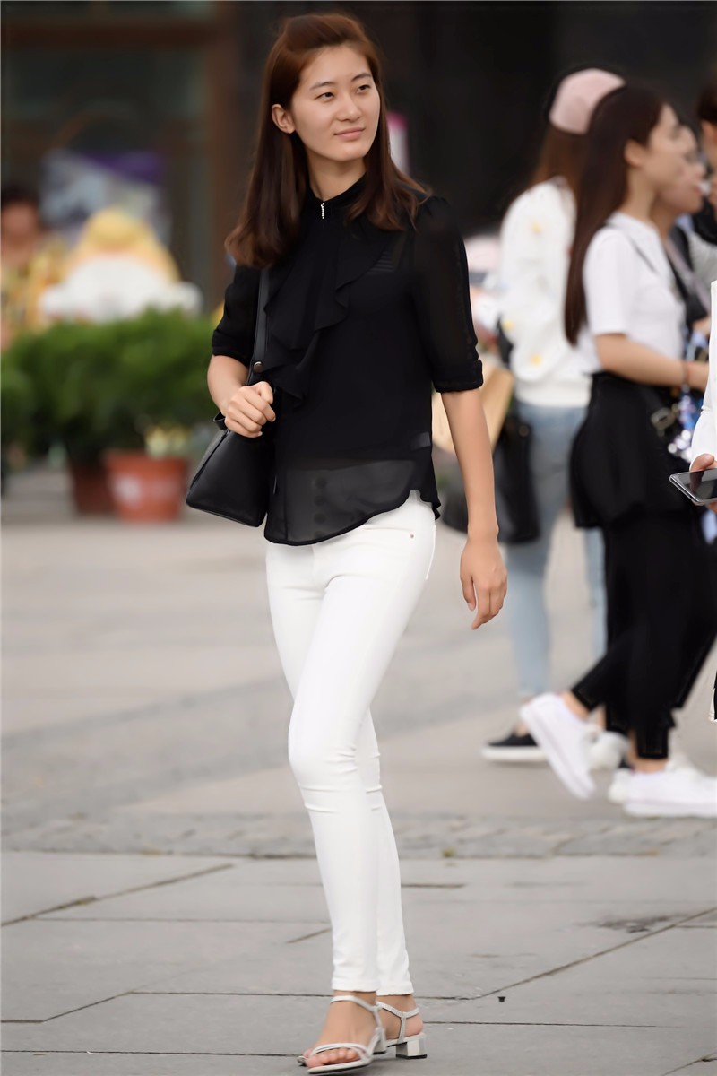 路人街拍,穿着黑衫白裤的凉鞋美女,微笑中透露着自信