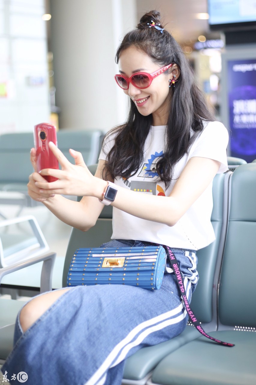 韩雪扎丸子头穿白t搭配牛仔裙现身机场,座椅上玩自拍少女心满满