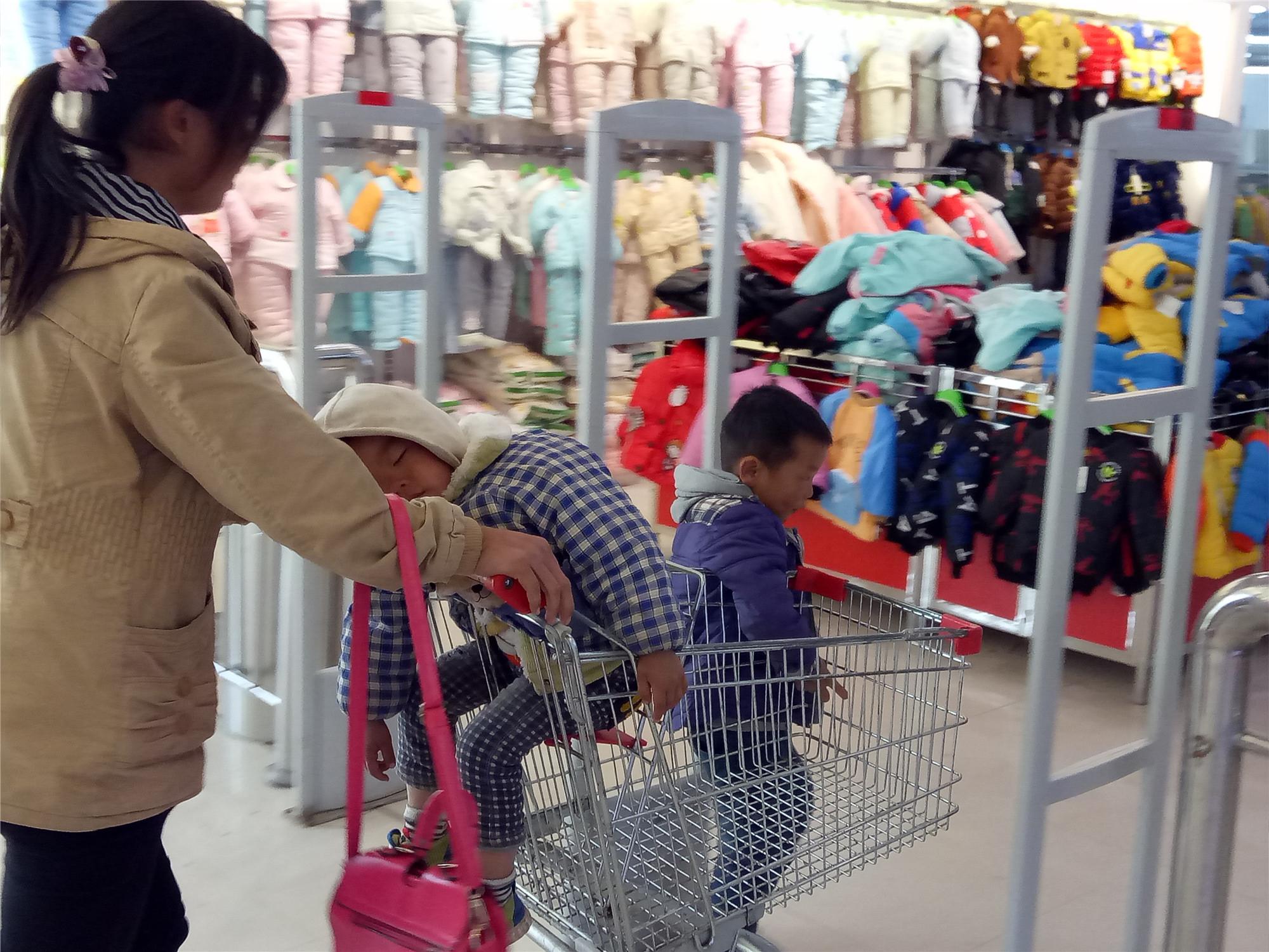农村母亲带孩子买衣服小儿子购物车睡着被大儿子推着到处跑