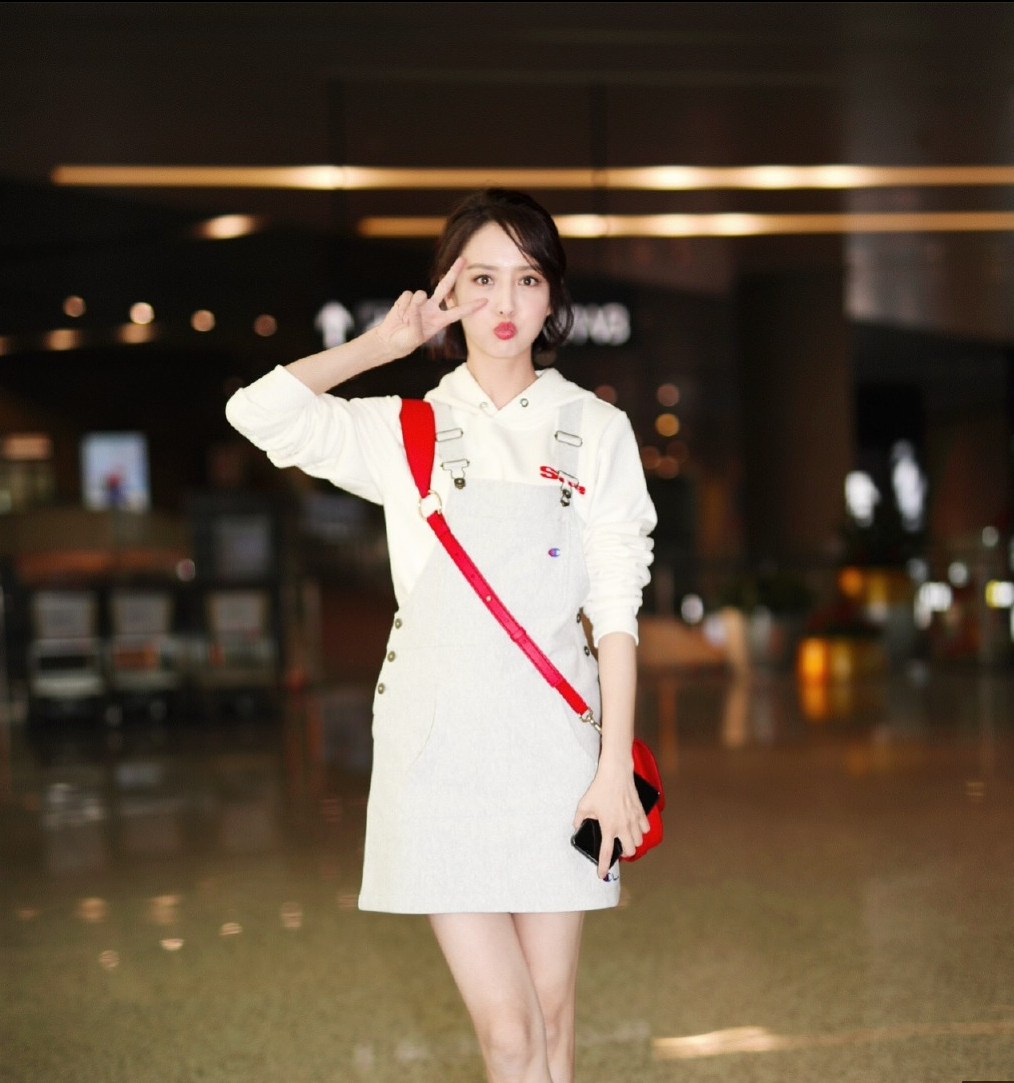 佟丽娅穿背带牛仔裤白色连帽卫衣现身机场 青春洋溢时髦亮眼