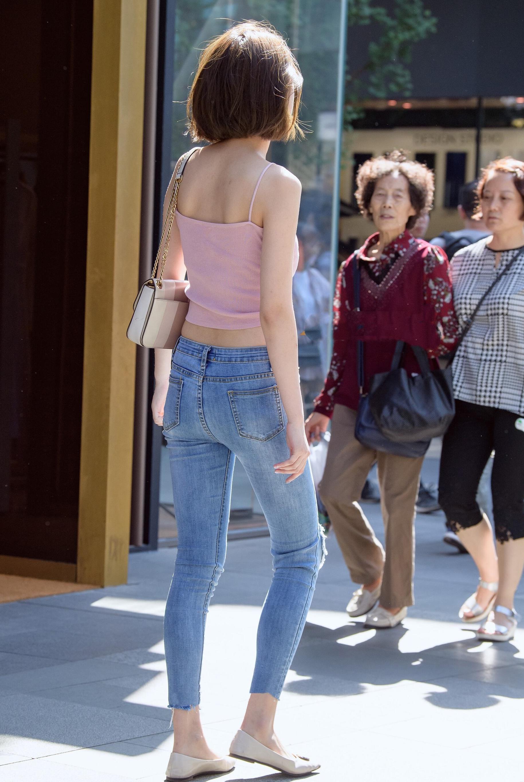 街拍紧身牛仔裤配粉色吊带上衣小姐姐身材凹凸有致打扮迷人