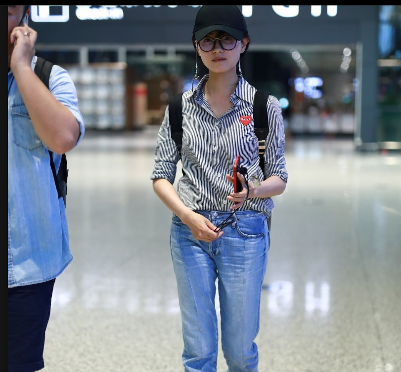 万茜戴棒球帽穿条纹衬衫现身机场 笑容灿烂比