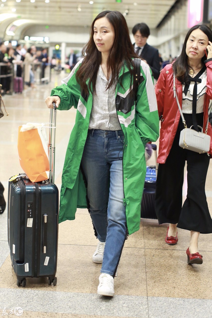 小陶虹绿色风衣搭配蓝色牛仔裤现身机场推着拉杆行李箱面带微笑