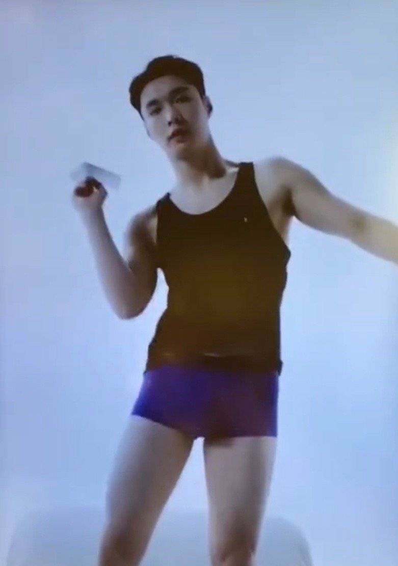 图中的张艺兴身穿着一件黑色背心,下身穿着四角内裤,双手将上衣掀了